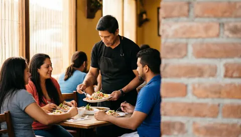 Waiter in black apron serving ceviche to friends at a family restaurant with brick wall for text
