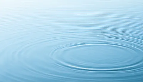Close-up of blue water with gentle circular ripples, creating a serene and relaxing atmosphere suitable for spa and massage backgrounds.
