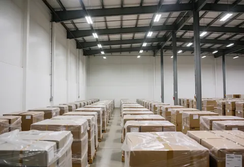 Spacious modern furniture warehouse with packed boxes on pallets, industrial lighting, and white walls