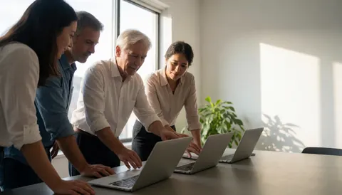 Four technical support professionals review laptops in a bright modern office with natural light and copy space on the right