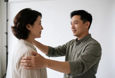 A photographer guides a model during a photoshoot with a white background, using friendly and natural gestures.