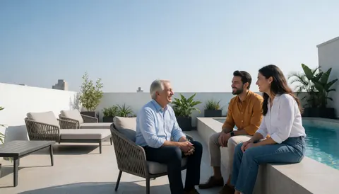 Three people talking happily on a hotel terrace with a pool, modern furniture, and a city view