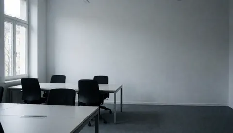 Empty modern office space with black tables and chairs, gray walls, and natural light from a window, suitable for text overlay
