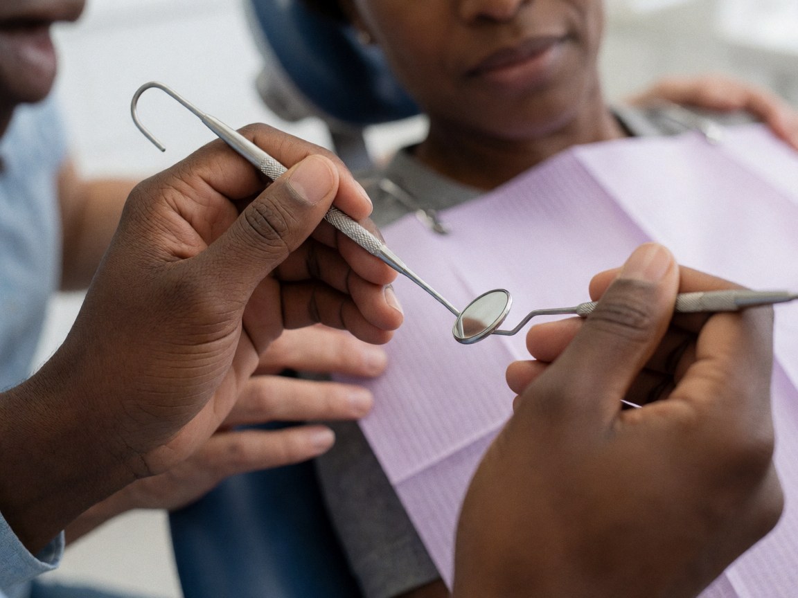 Close-up of professional hands holding dental tools with a patient in the chair in a clinical setting