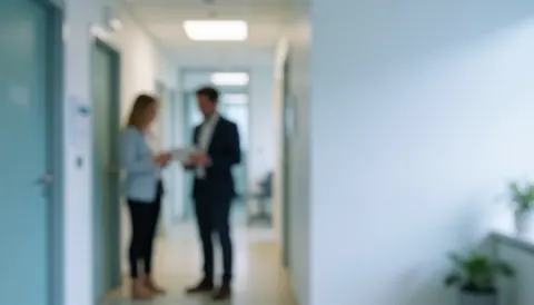 White clinic hallway with doors and two blurred people talking, with copy space on the right