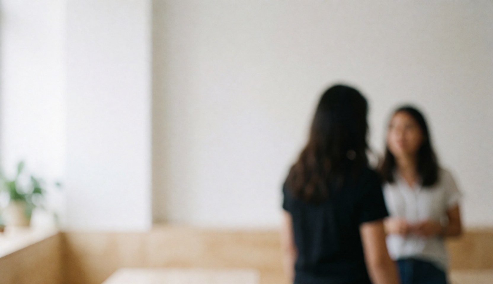 Two people talking in a bright coworking area with white walls and light wood furniture