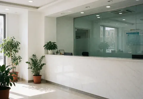 Bright medical clinic reception with white desk, green plants, and white walls ready for patients
