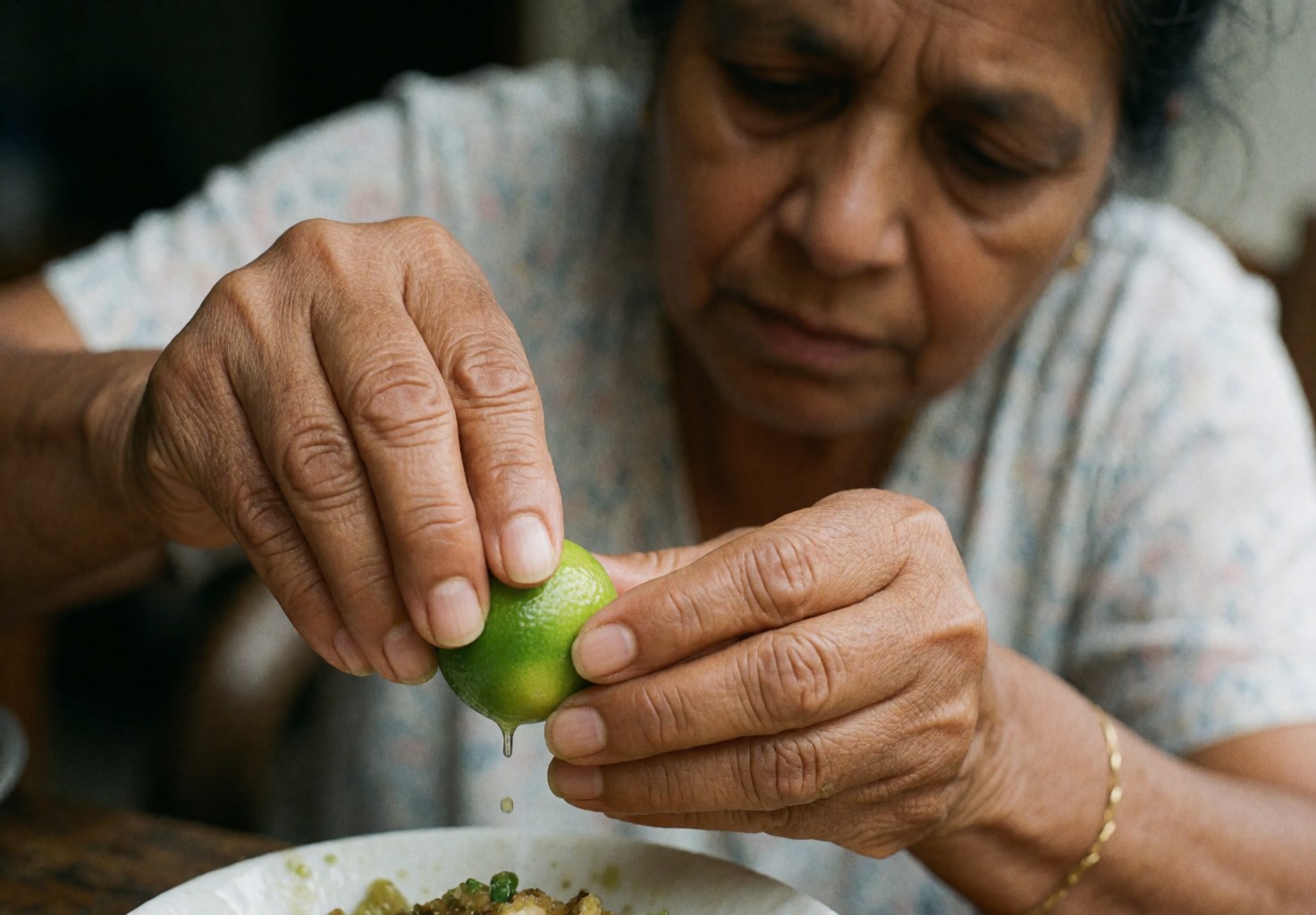 A woman squeezes fresh lime juice onto a dish of food with focused hands in a food truck setting