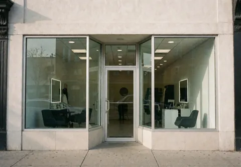 Exterior view of a modern dog grooming salon featuring glass windows, a main entrance, and visible interior chairs in a clean professional setting