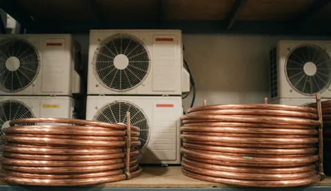 Industrial background featuring copper tube coils and air conditioning units on shelving with warm lighting and realistic texture.