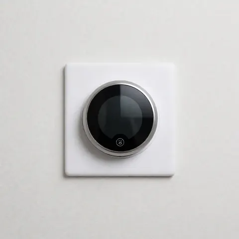 Modern digital smart thermostat mounted on a white wall with a minimalist design suitable for contemporary homes and offices