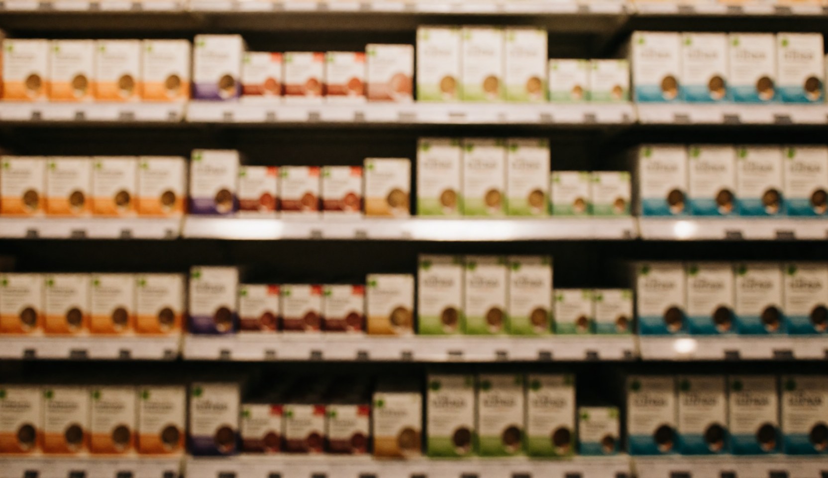 Warm toned blurred background of retail shelves stocked with nutrition supplements, providing copy space for business text