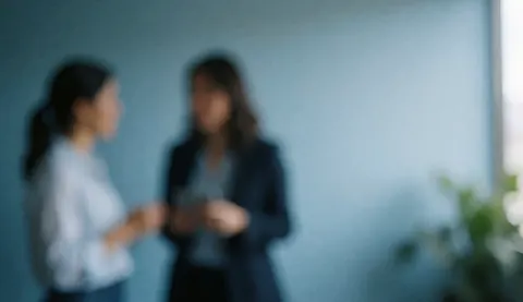Blue-toned office background with two blurred people conversing and ample copy space on the right for financial text