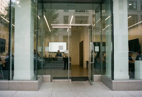 Bright modern glass office entrance showing employees working inside, conveying a professional and clean atmosphere for tech startups.
