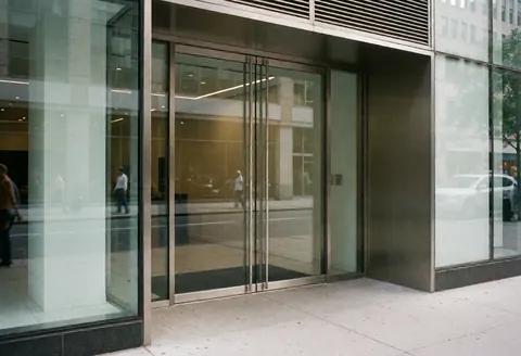 Glass entrance to a modern coworking space with street reflections and a professional atmosphere