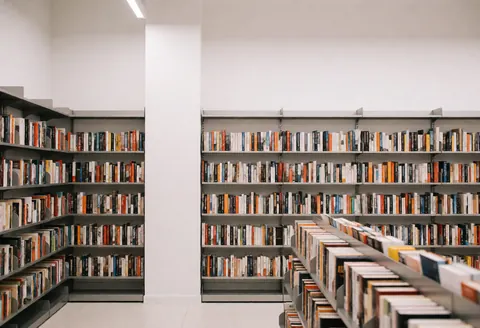 Interior of a modern bookstore featuring metal shelves filled with books, white walls, and light flooring