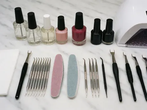 Set of manicure tools and nail polishes organized on a white marble surface, ideal for beauty salons