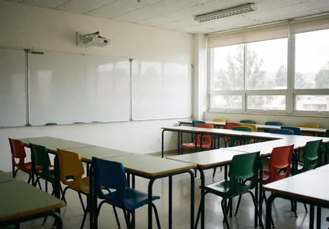 Empty language school classroom featuring colorful chairs, a whiteboard, and large windows with natural light creating a clean and welcoming learning environment