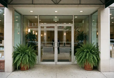 Clean and professional spa entrance featuring glass doors and potted green plants for a welcoming business exterior.