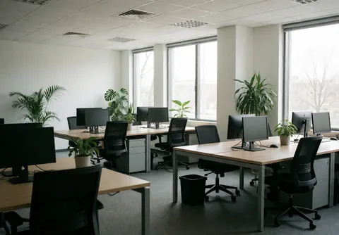 Empty modern office space featuring desks, chairs, computers, and plants, ideal for human resources and professional environments