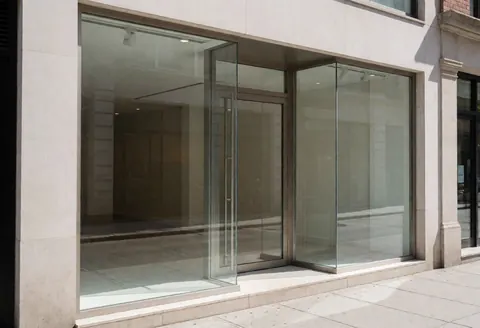 Modern office facade with large glass windows and entrance door, empty interior with no people or furniture visible.