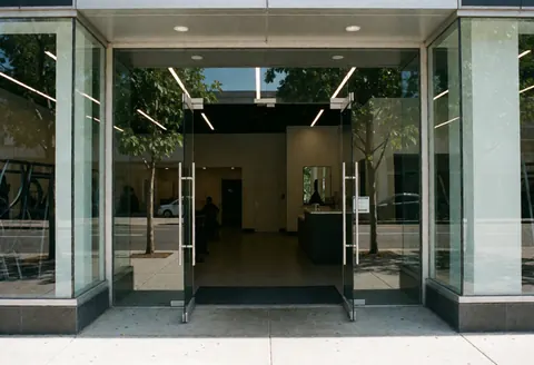 Modern building entrance with glass doors and reception desk inside.
