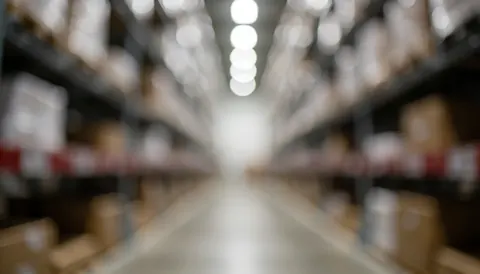 Blurred warehouse aisle with shelves and lights, everything out of focus.