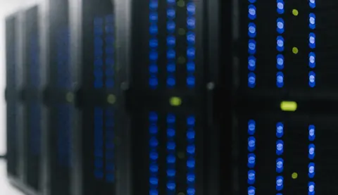 Black servers in server room with blue and green lights illuminated.