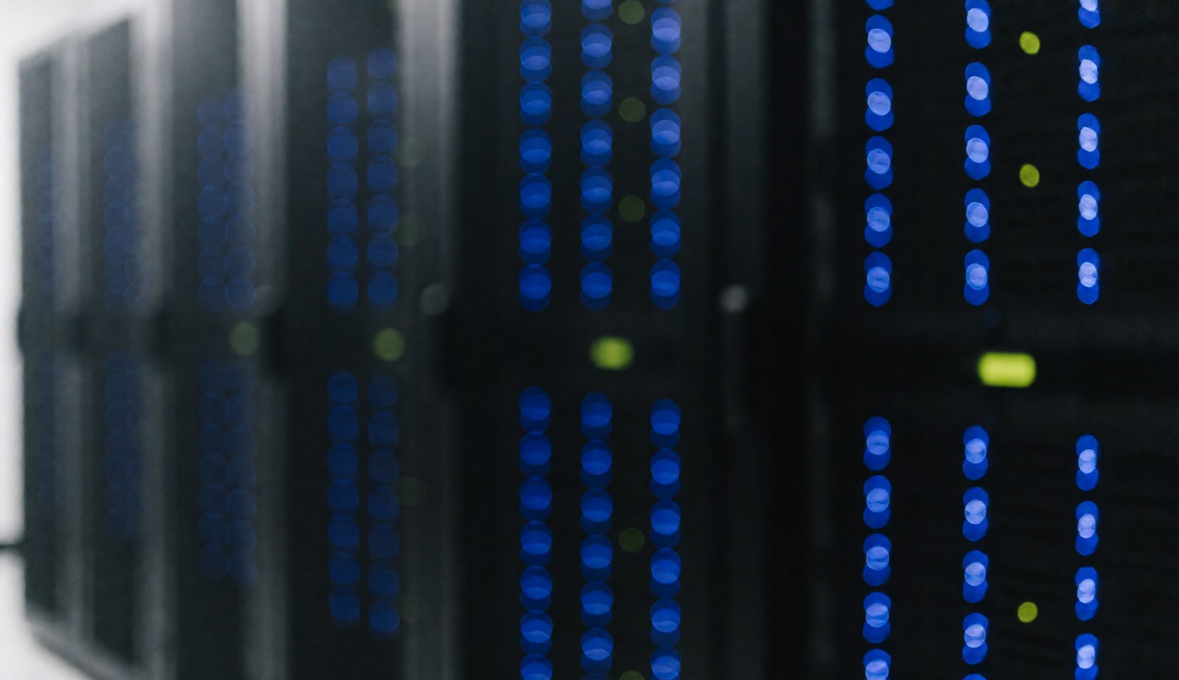 Black servers in server room with blue and green lights illuminated.