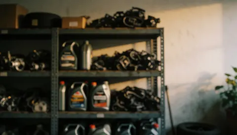 Warmly lit mechanic workshop background featuring shelves stocked with auto parts and oil bottles, providing a textured surface ideal for text overlay.