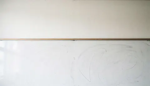 Clean whiteboard background with faint chalk marks, ideal for educational text overlays in university settings