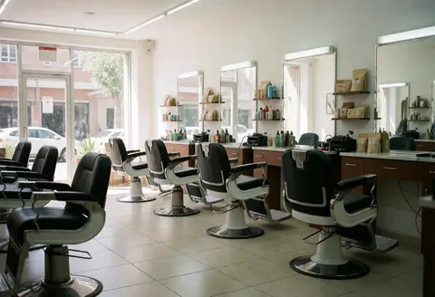 Modern barbershop with black chairs, mirrors, and shelves with products.