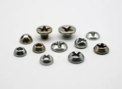 Close-up of various metal Phillips head screws arranged on a plain white surface for hardware store use