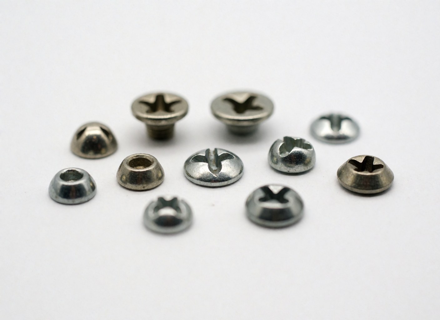 Close-up of various metal Phillips head screws arranged on a plain white surface for hardware store use