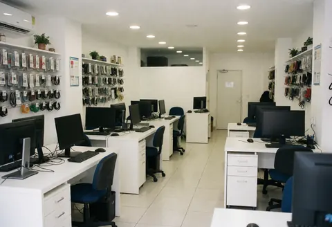 Clean and professional it support office interior featuring desks, monitors, chairs, and neatly organized cable shelves