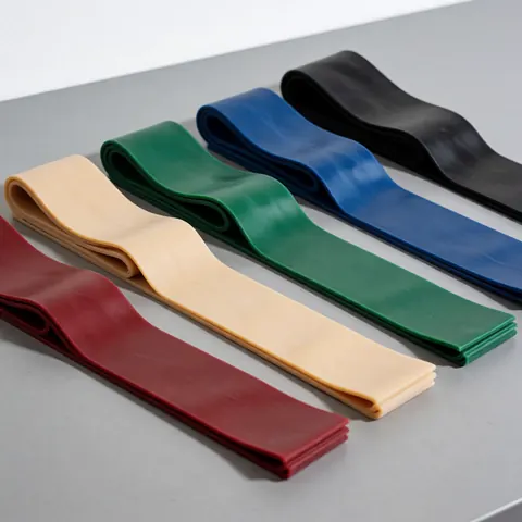 Five resistance bands in different colors, red, beige, green, blue, and black, arranged diagonally on a gray surface.