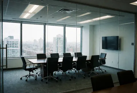 Empty conference room with black tables and chairs, glass walls, and panoramic city view ideal for real estate