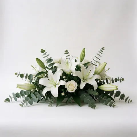 White lilies, roses, and eucalyptus arranged as a wedding centerpiece on a white background for event catalogs
