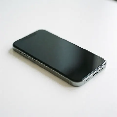 Sleek modern smartphone with metallic edges and screen visible on a clean white surface with professional lighting