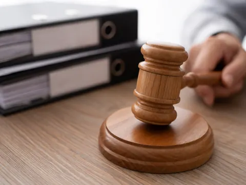 Close-up of a wooden judge's gavel resting on a black legal file folder in a well-lit office setting