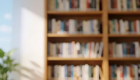 Blurred background of bookshelves in a library with natural light and some greenery on the left side