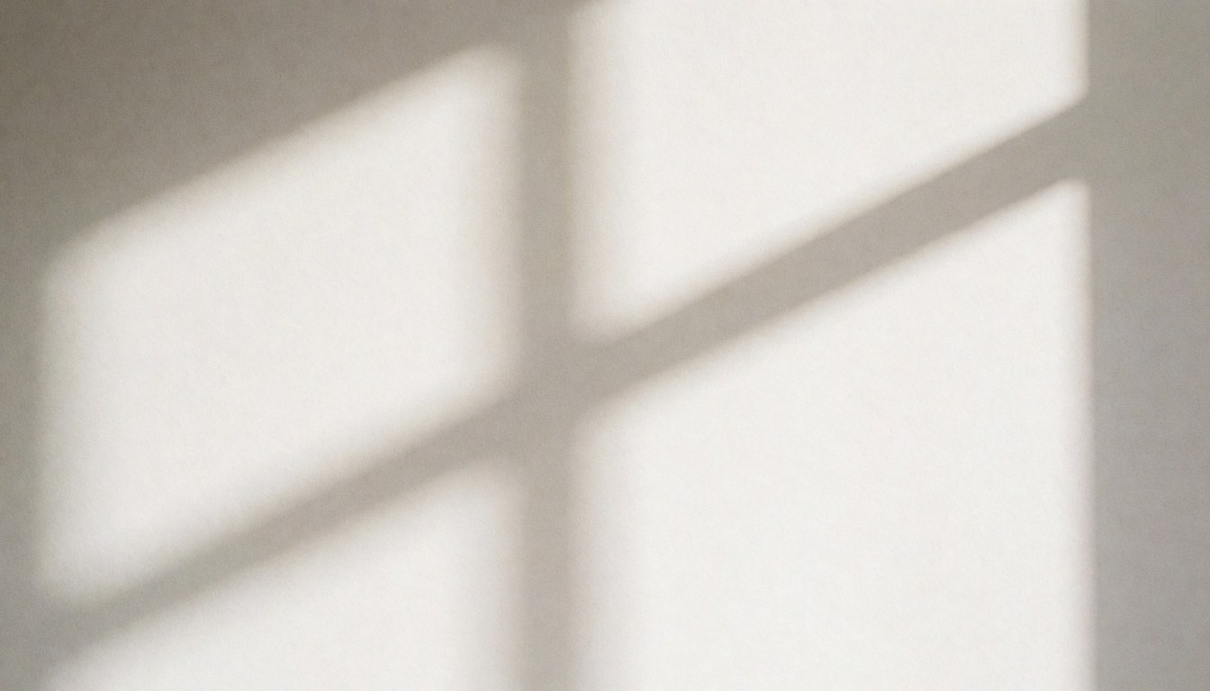 Soft shadow of a window blind cast on a light gray wall, providing a minimalist background for business presentations or websites.