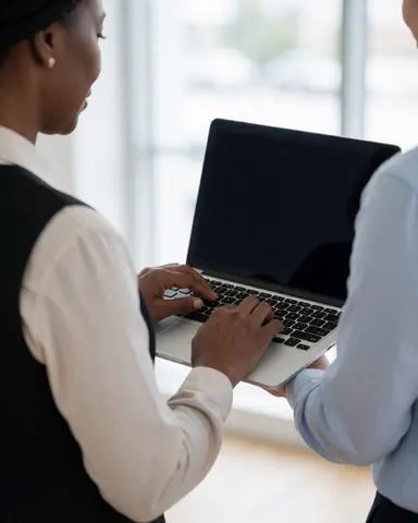 Close-up view of hands typing on a laptop keyboard with the screen visible, set in a clean, professional office environment for business teams.