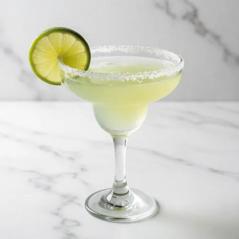 Margarita cocktail with lime and salt in a glass on white marble surface, bright clean lighting, ideal for restaurant or bar product display