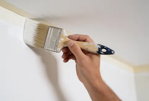 Close-up of a clean, professional brush stroke applied to a white interior wall, showcasing precise painting technique and smooth texture.