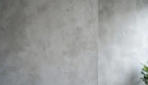Textured gray industrial concrete wall serving as a clean background with ample negative space on the right for business text or logos.
