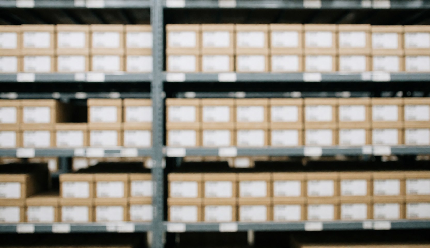 Out of focus background of organized warehouse shelves and stacked cardboard boxes suitable for logistics text overlay