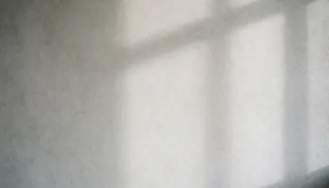 Close-up view of a smooth gray concrete wall surface with soft natural lighting and subtle shadows, ideal for architectural design and interior projects