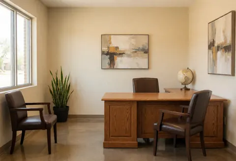 Reception office with wooden desk, chairs, plant, and wall art, ready to serve clients.