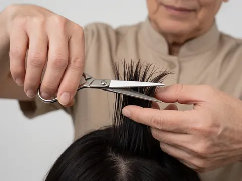 A hairdresser cuts a client's hair with scissors in a hair salon.